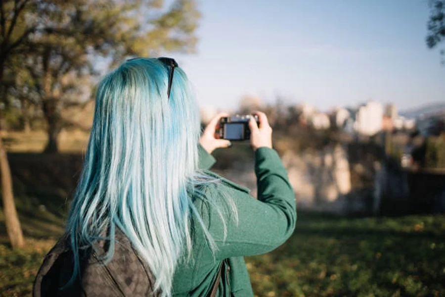 Le dos d'une fille aux cheveux bleus photographiant la ville