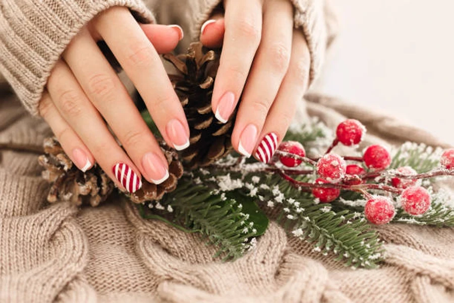 Zuckerstangen-Nägel auf der Hand einer Frau, die einen Tannenzapfen hält