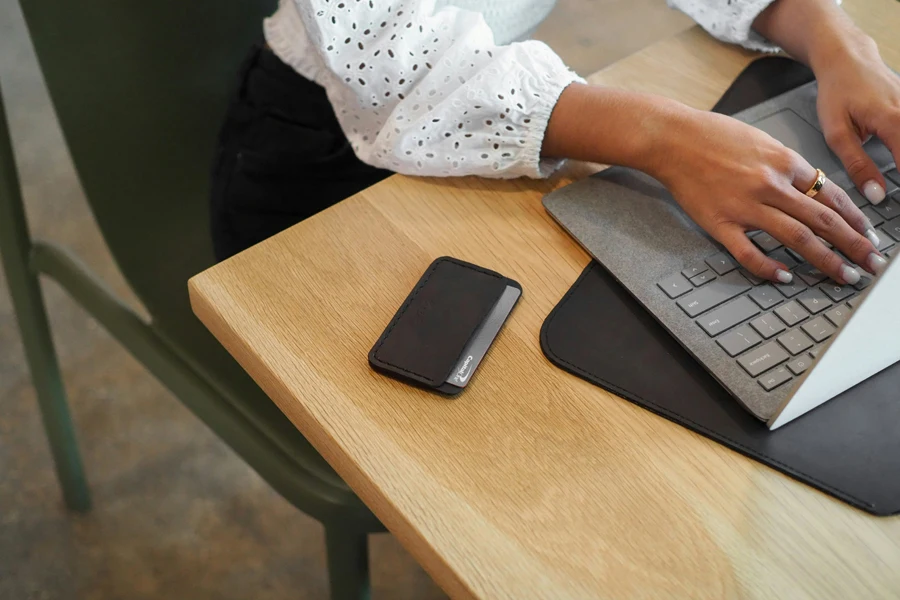 Card case next to woman working on laptop