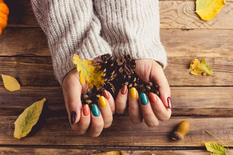 Fall nails in different colors with hand holding leaves