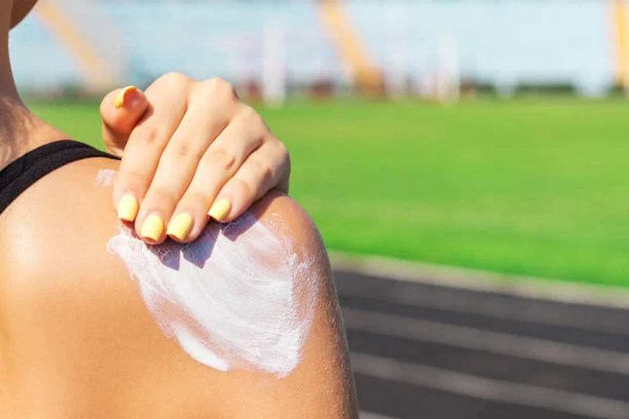 Une femme en forme applique de la crème solaire sur son épaule