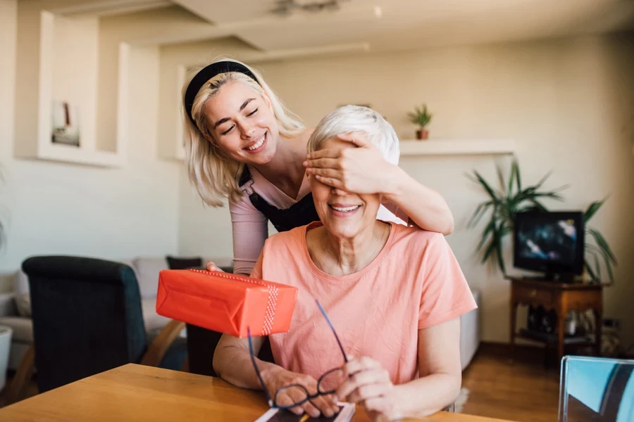 Girl covering her mother's eyes while presenting her a gift