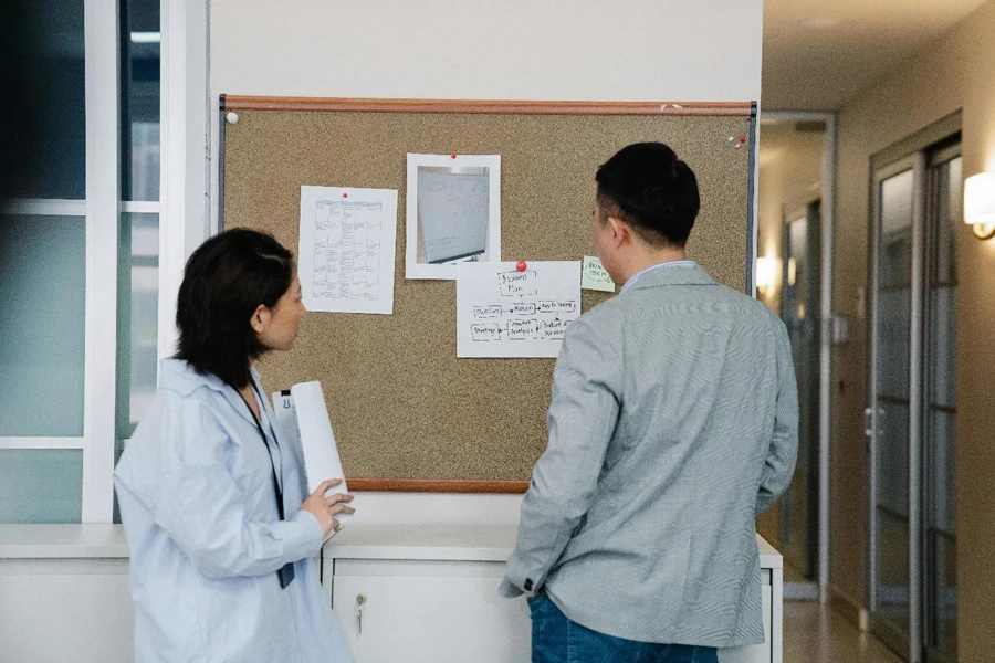 Man and Woman Looking at Notices on a Cork Board