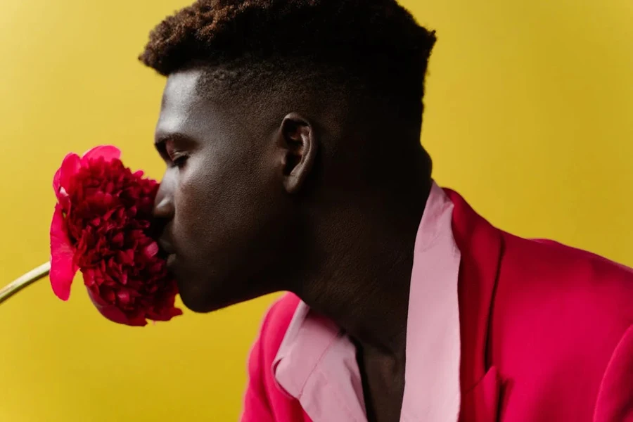 Man in red suit smelling a red flower