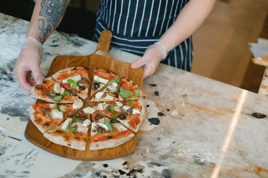 Pessoa exibindo uma pizza caseira em uma tábua de servir