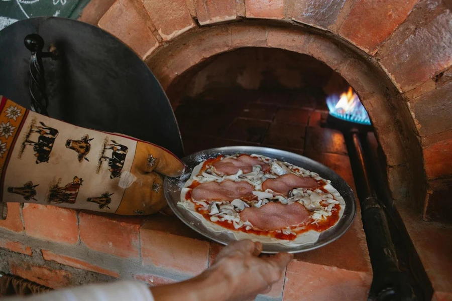 Pessoa colocando uma chapa de pizza em um forno