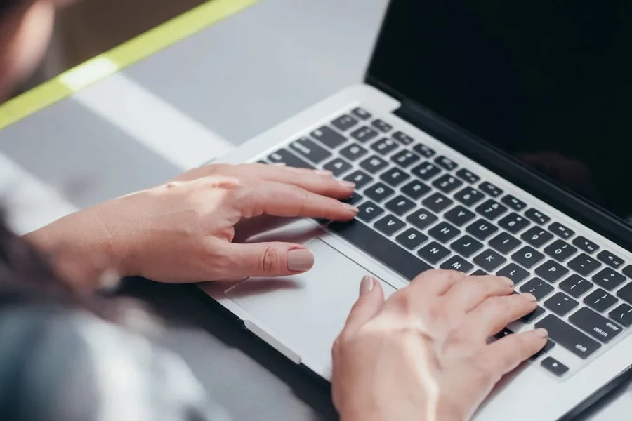 Orang mengetik di laptop perak