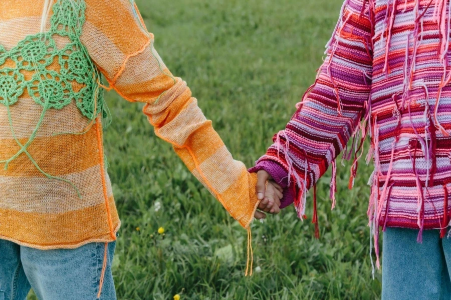 Des personnes portant des pulls tricotés à rayures se tenant la main