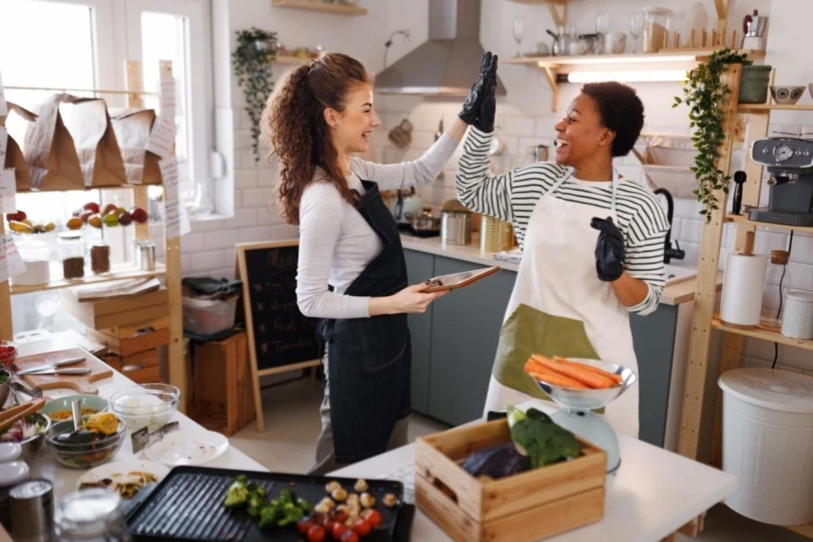 Deux jeunes femmes chefs souriantes se félicitent en travaillant dans leur petit magasin d'aliments biologiques