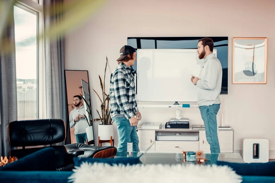 Two males writing on a whiteboard teaching