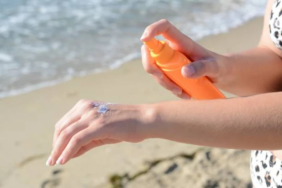 Mujer aplicándose crema de protección solar en la mano en la playa