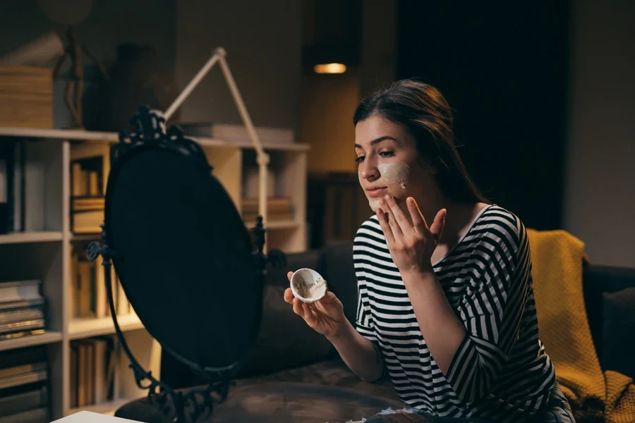 Woman applying skincare products at night