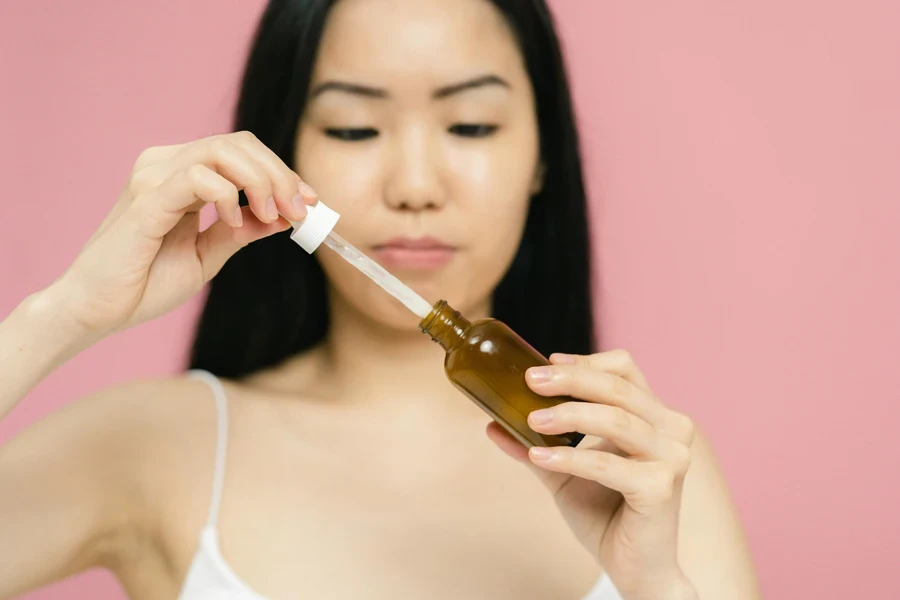 Mujer sosteniendo una botella de producto cosmético y una pipeta