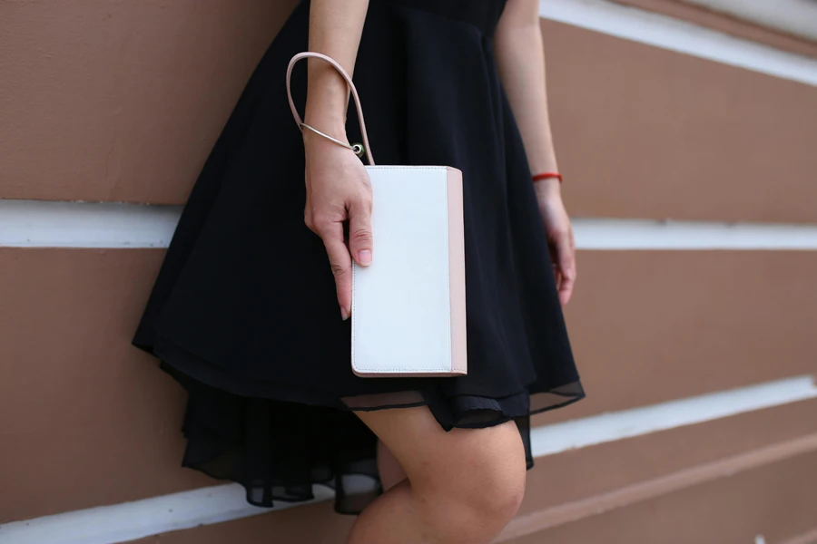 Woman holding white and pink wristlet