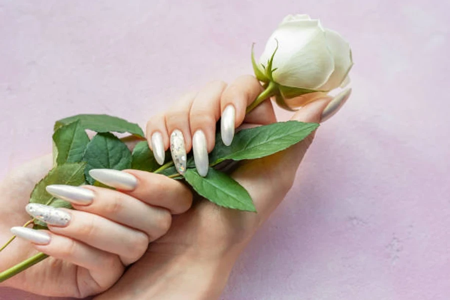 Woman holding white rose with iridescent pearl nail polish