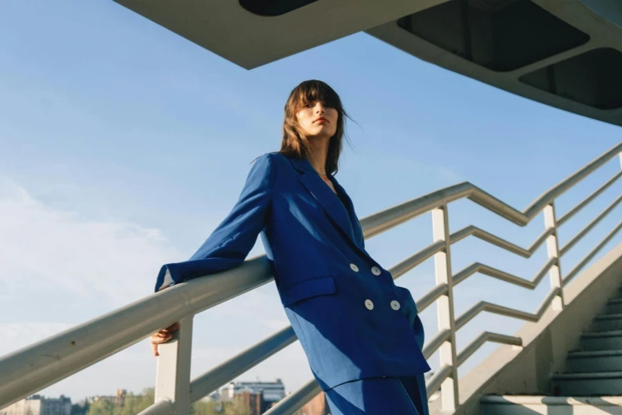 Femme en vêtements bleus appuyée sur une balustrade en métal