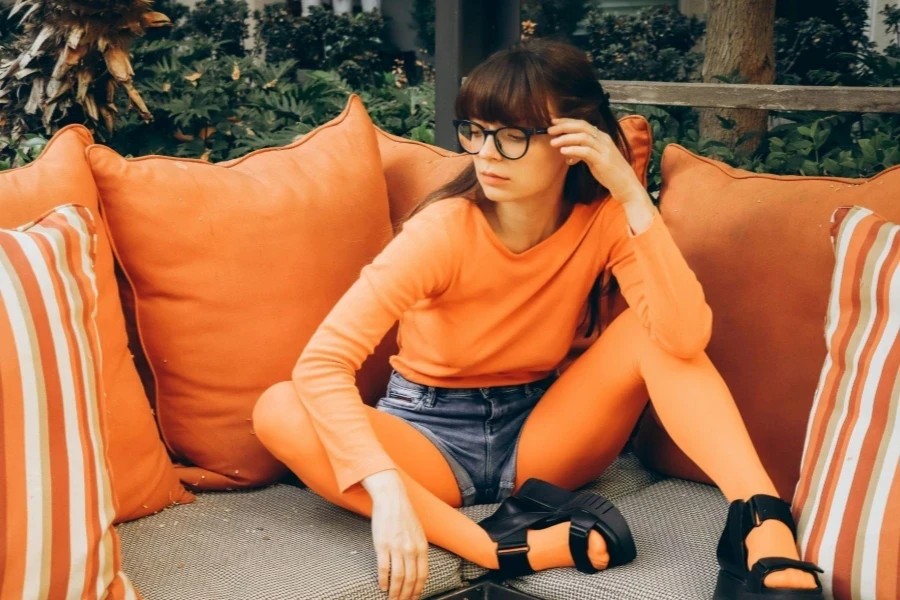 Femme en vêtements orange assise sur un canapé de patio