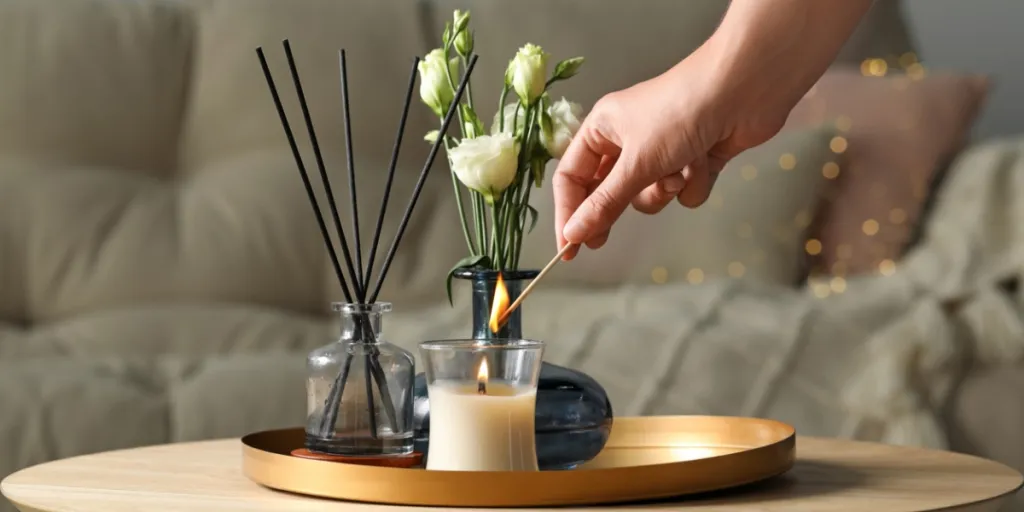 Woman lighting a candle near a scent diffuser