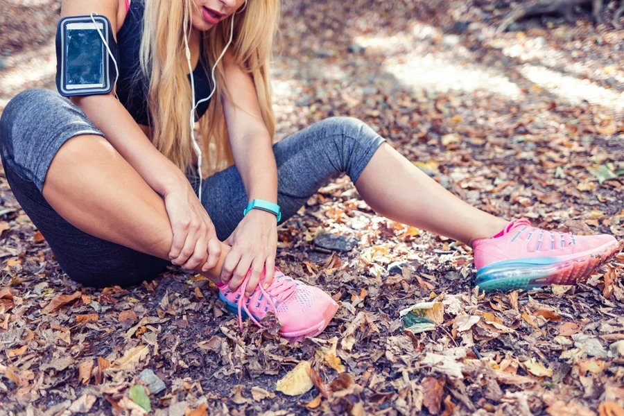 Woman massaging her ankle in knee-length leggings