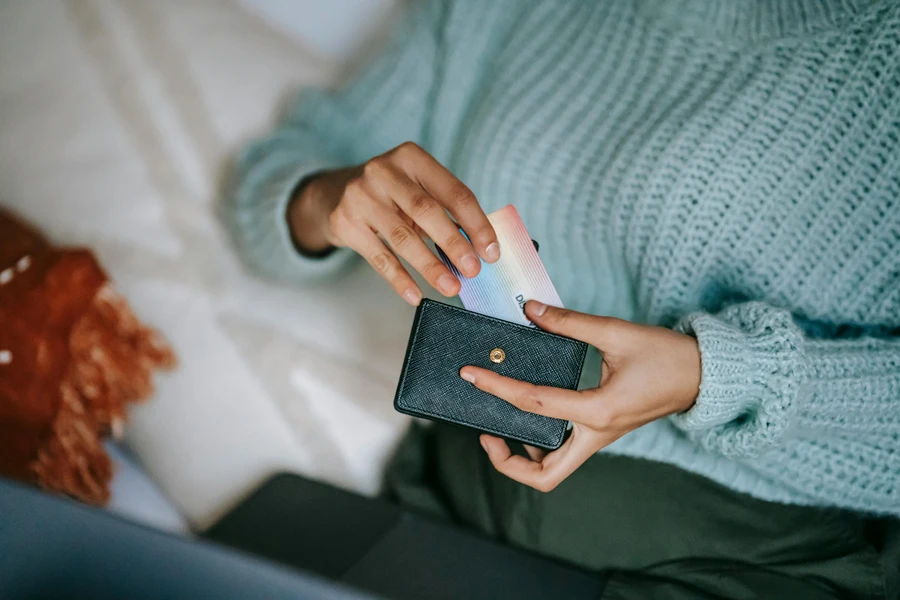 Woman putting credit card into saffiano leather wallet