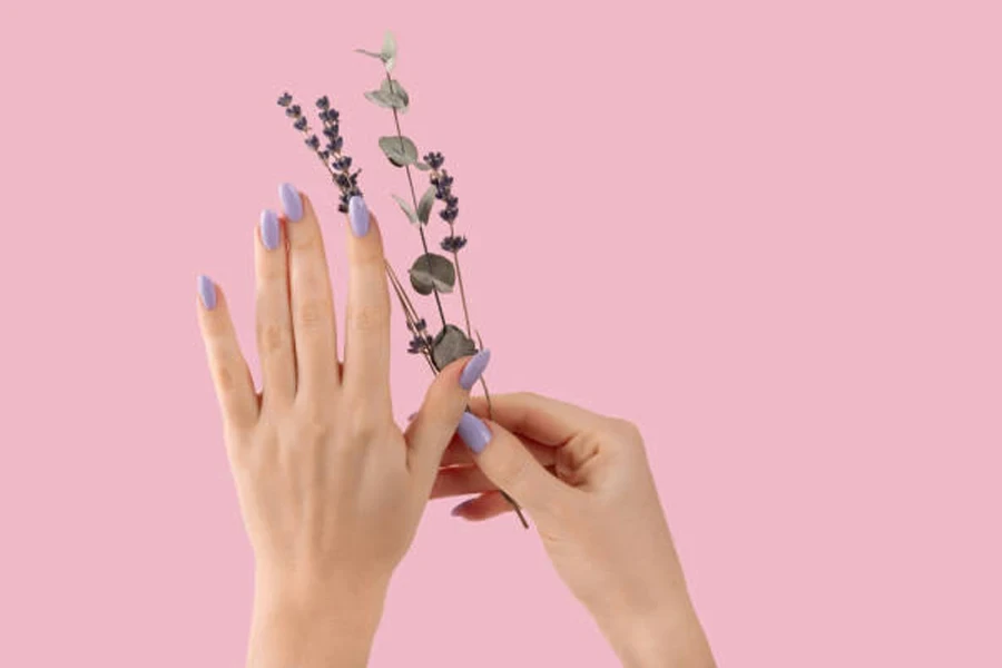 Woman wearing dusty lavender nail polish against pink wall