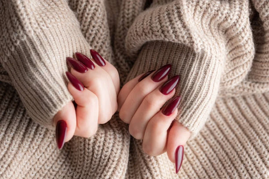 Woman wearing winter cream sweater with deep burgundy long nails