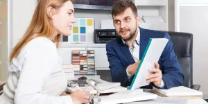 Une jeune cliente discute avec un vendeur d'un accord sur l'achat de meubles dans une salle d'exposition