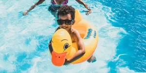 Un niño en una piscina sosteniendo un patito inflable.