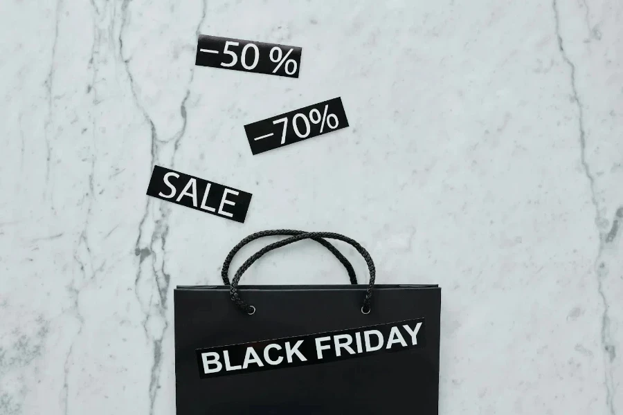 Saco de papel da Black Friday e placas de vendas com desconto em um fundo de ladrilho de mármore