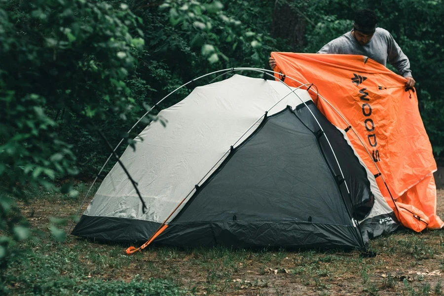 tenda arancione e grigia su campo di erba verde durante il giorno