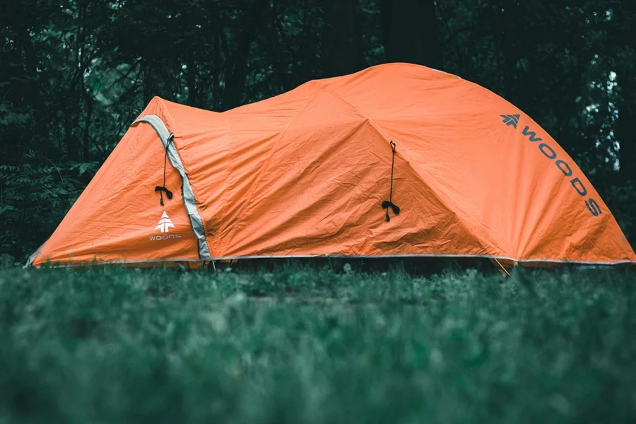 tenda arancione su campo di erba verde durante il giorno