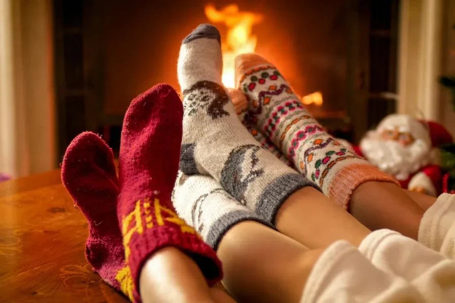 Parents and child in warm socks next to a fireplace