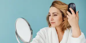 Mujer mirándose el cabello en un pequeño espejo