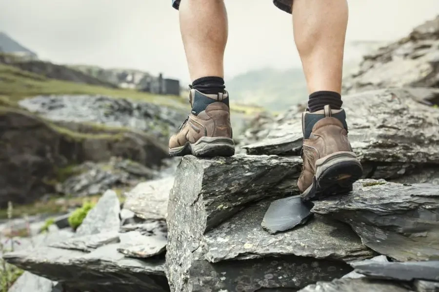 Caminhante caminhando sobre pedras em uma trilha de montanha