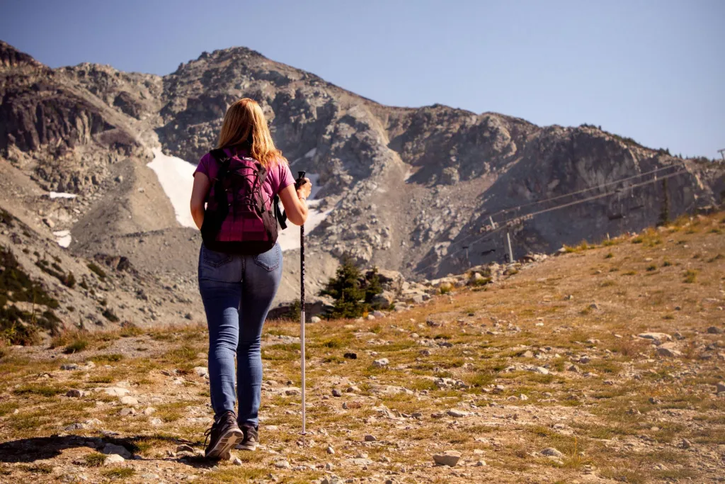 Una donna che fa un'escursione su un sentiero panoramico di montagna in una giornata limpida, abbracciando l'avventura