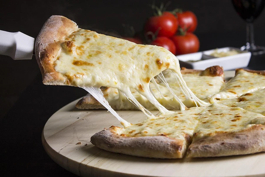 A cheese pizza being held by a person