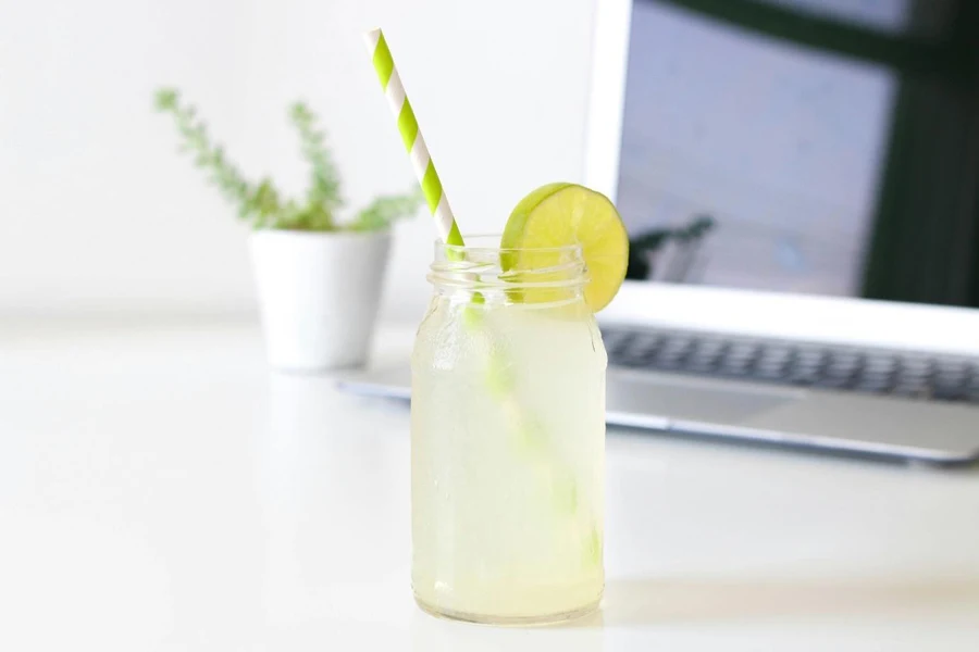 A glass jar with a straw and a lime slice on it