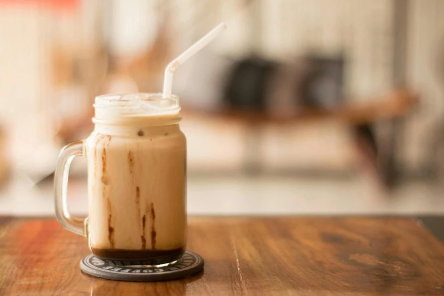 A glass mug with a straw filled with a brown liquid