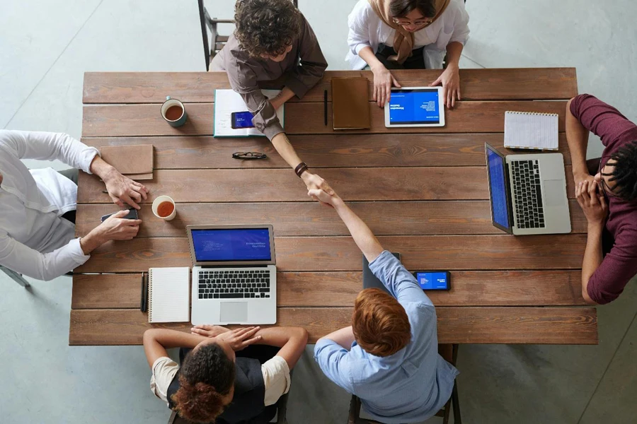 Un grupo de personas alrededor de una mesa con computadoras portátiles.