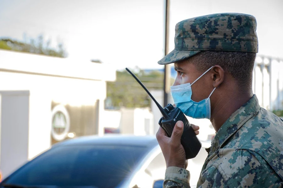 Um soldado usando uma máscara facial e segurando um walkie talkie