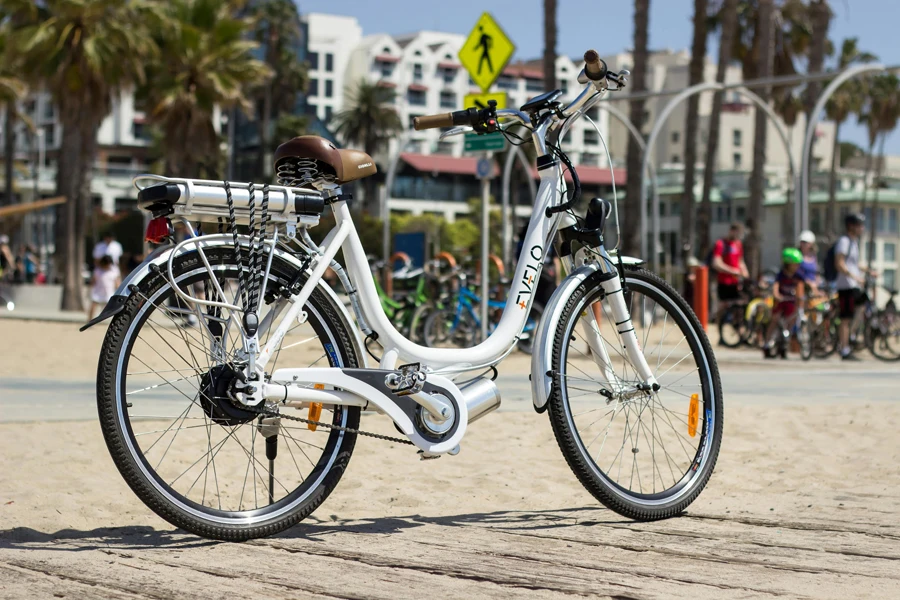 A white electric bike is parked on the beach