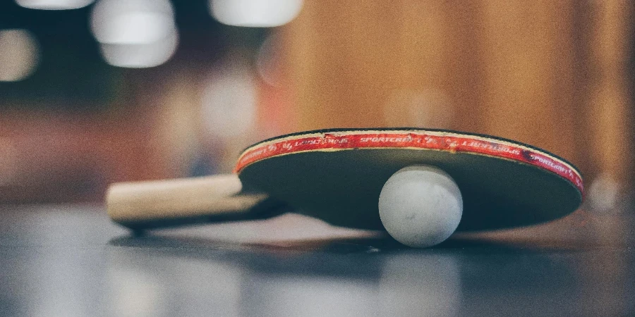 Primo piano di una racchetta da ping pong e di una pallina su un tavolo