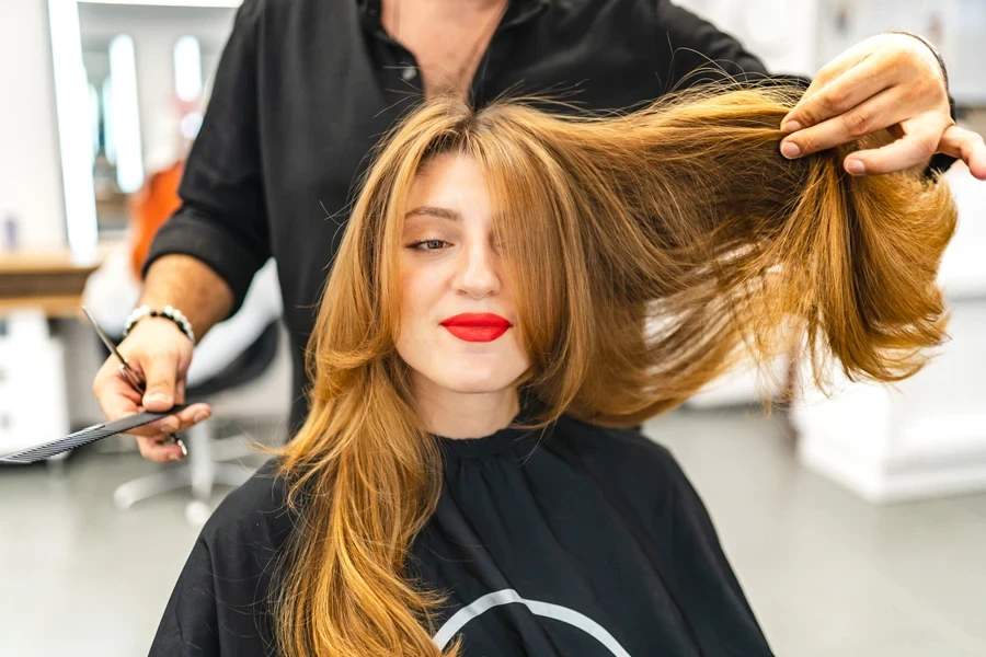 Coiffeur coiffant les cheveux d'une cliente