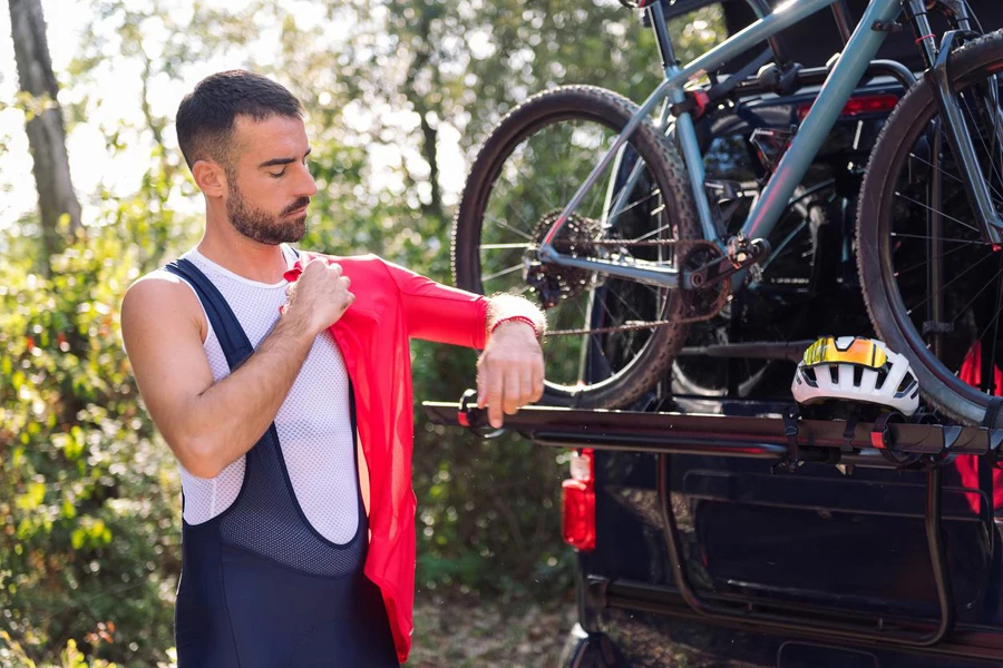 Hombre se viste junto a su camioneta para ir en bicicleta