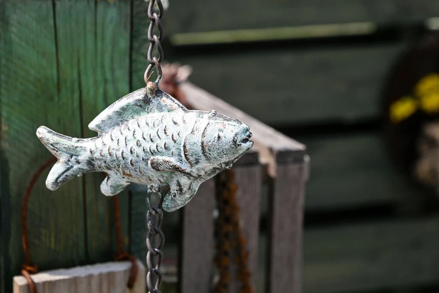 Cadena de lluvia de metal con forma de pez en un jardín