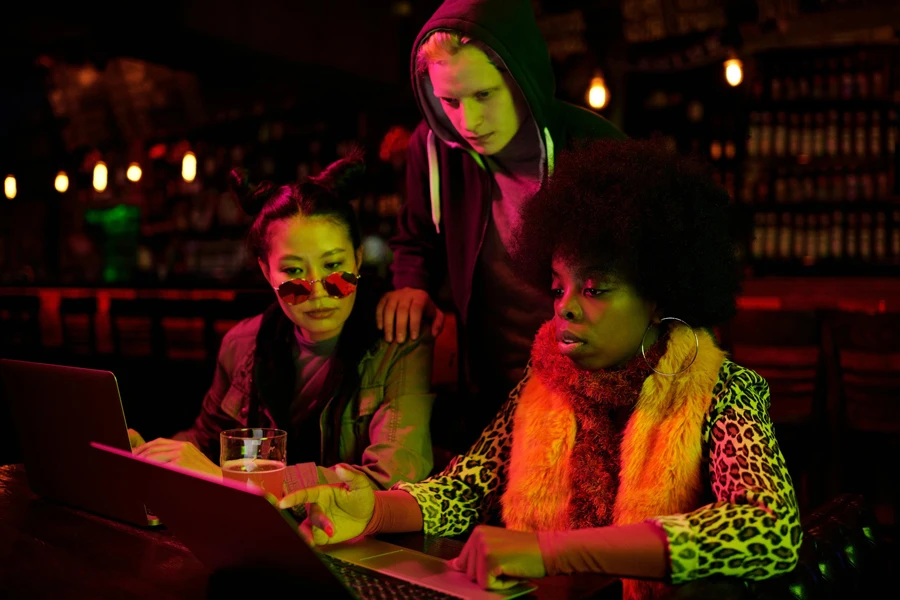 People Looking at a Laptop in a Bar