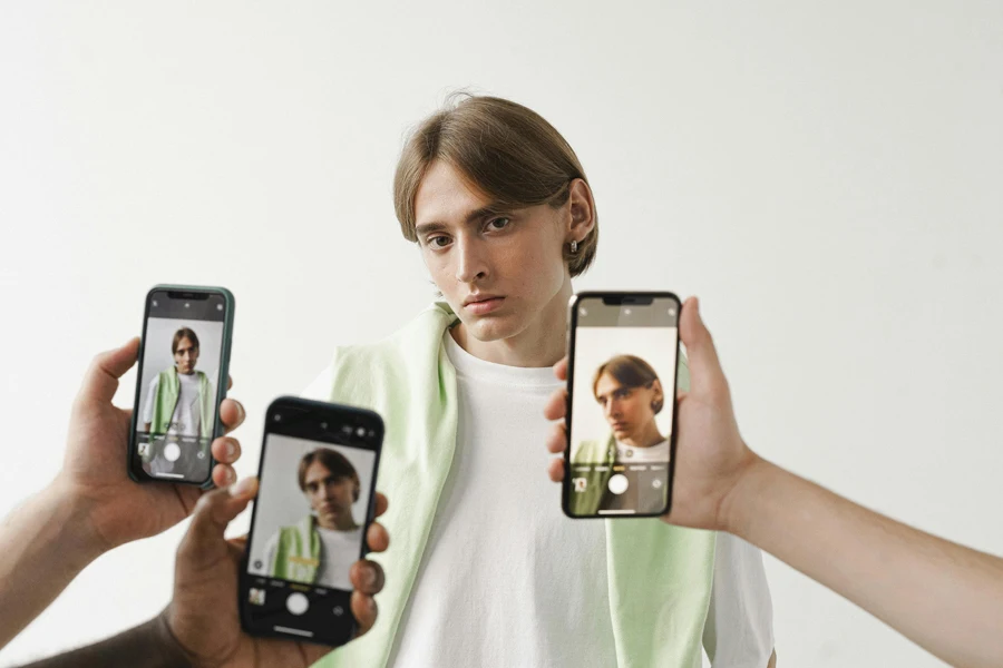 Personas tomando fotografías de un hombre con camisa blanca usando teléfonos móviles