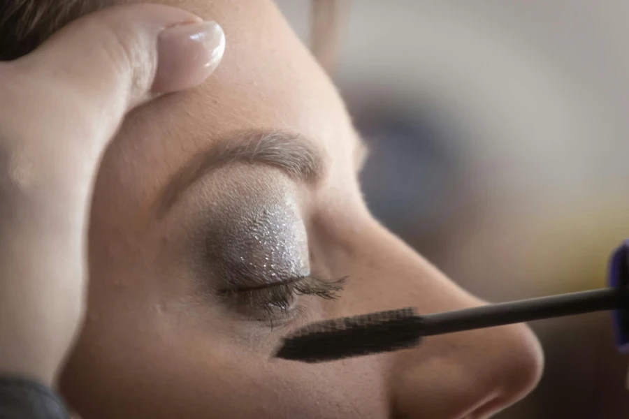 Personne mettant du mascara sur une femme