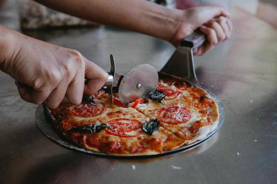 Orang yang sedang mengiris pizza