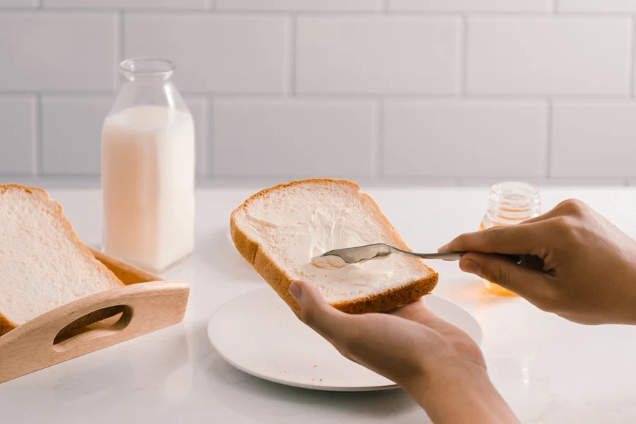 Mengoleskan mentega pada sepotong roti